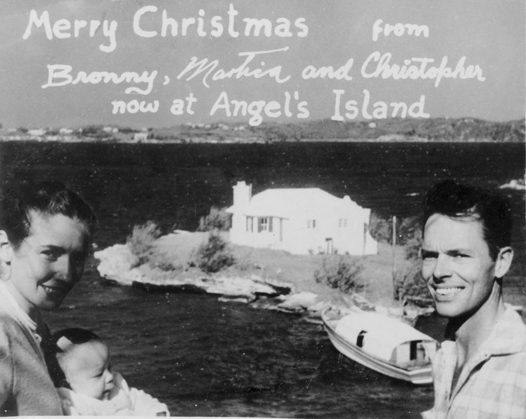 Black and white photo taken in 1955 of Mr. and Mrs. Bronson Hartley, in Bermuda with Harrington sound in the background, with home on angel's island in the center.