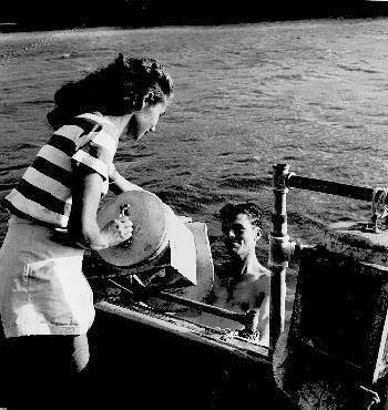 Bronson Hartley's wife lowering his diving helmet into the water in the early days of Bermuda